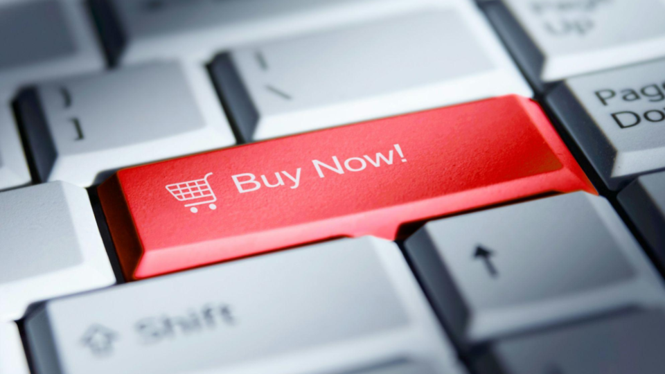 Teclado de computador em grande plano destacando uma tecla vermelha com a mensagem "Buy Now!" (Compre Agora) e um ícone de carrinho.